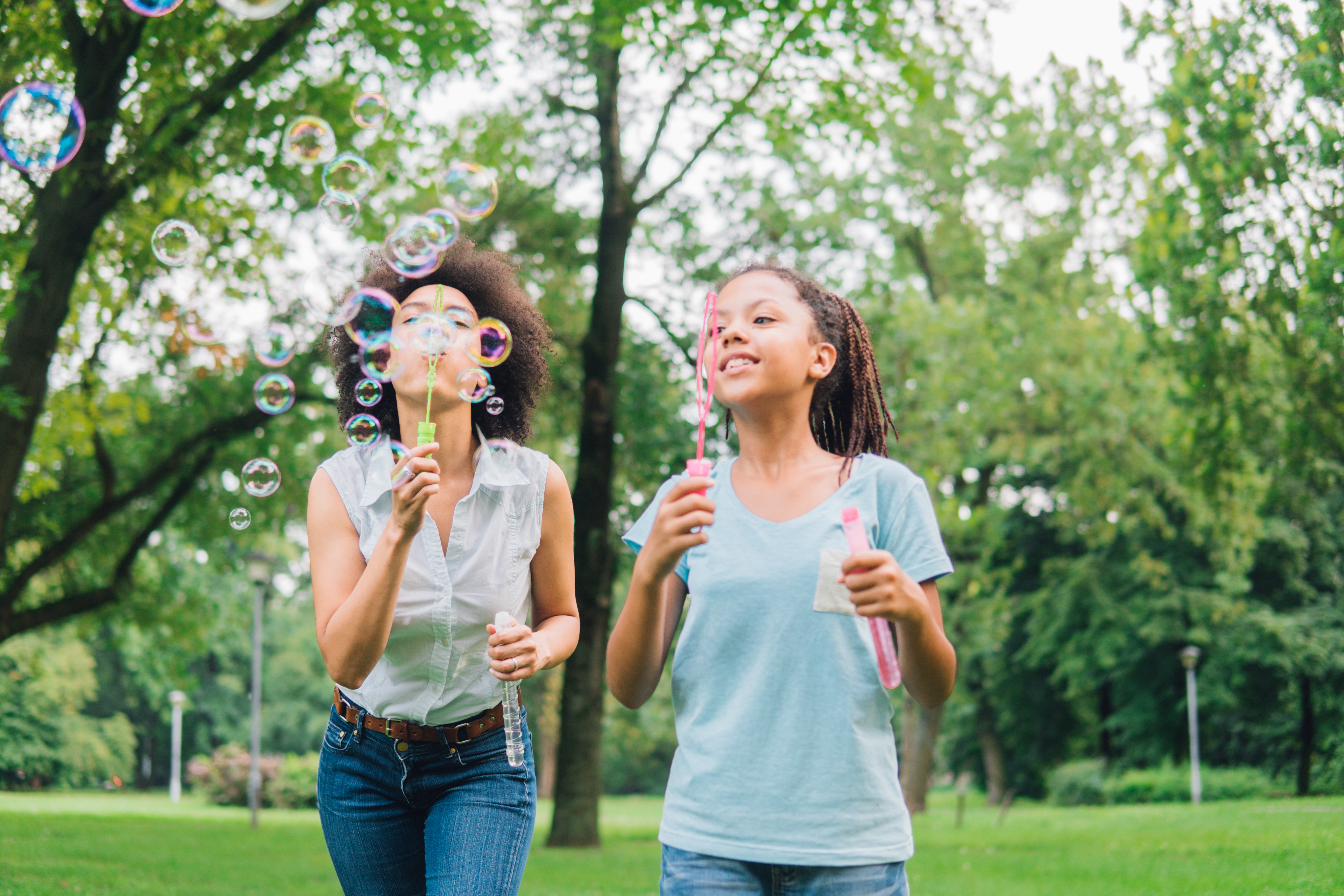 mom blowing bubbles with young girl and boy in park