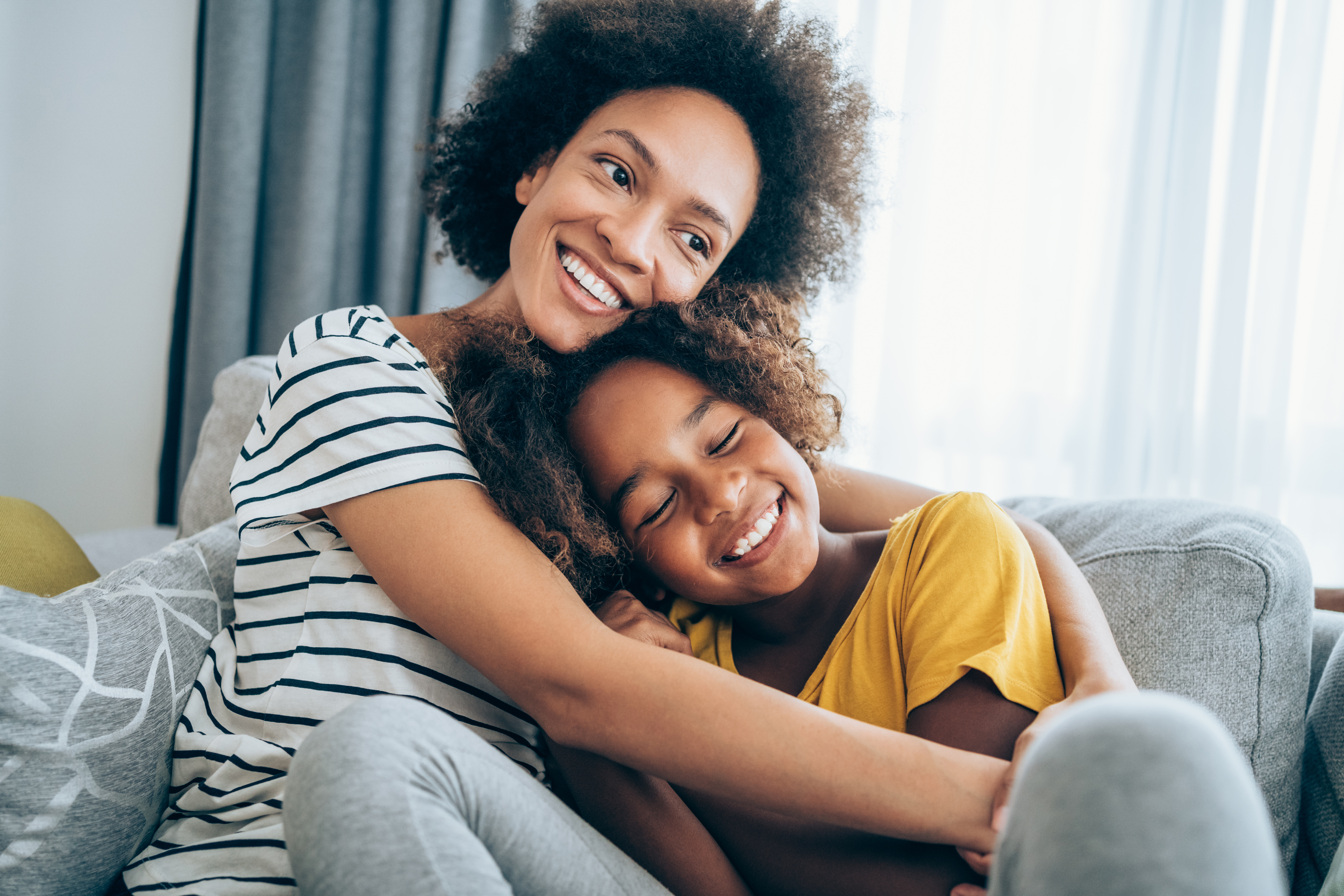 mom hugging young daughter and both are smiling