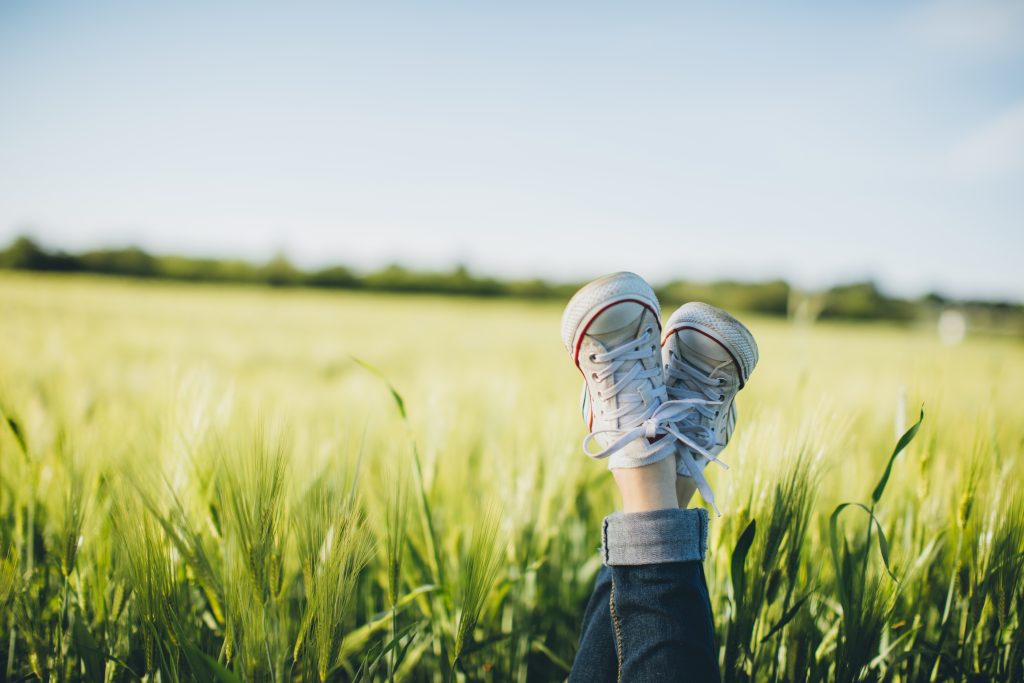 Kid with sneakers relaxing in field