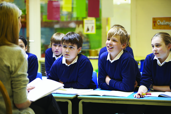 Middle school students in uniform listening to teacher