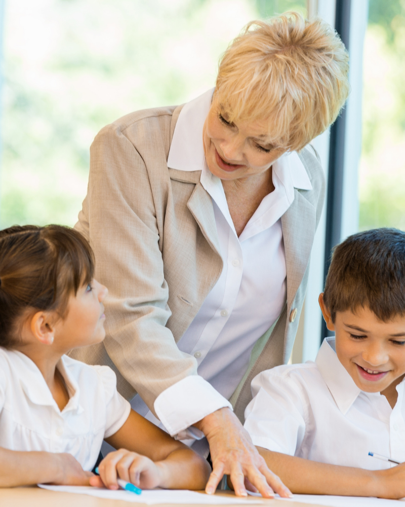 older female teacher educating 2 Catholic school students